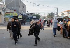 A displaced Palestinian man, who fled his house due to Israeli strikes, carries his belongings as he makes his way back to his home, in Khan Younis